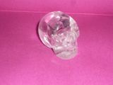 a crystal skull sitting on a pink surface