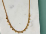 un collier plaqué or posé sur une dalle de marbre