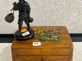 une petite boîte en bois sur laquelle trône une figurine