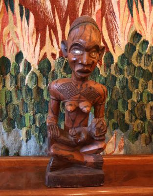 une statue en bois représentant un homme assis sur une table