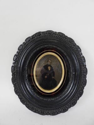 an old picture of a woman in a black dress is hanging on a wall