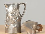 a silver pitcher sitting next to a teapot on a table