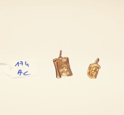 two small gold charms are sitting on a white surface next to a piece of paper