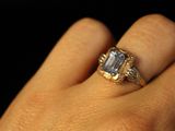 a woman ' s hand holding a ring with a diamond on it