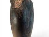 a black vase with a bird on it on a white surface