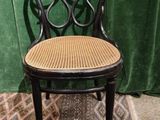 a black chair with a wicker seat on a rug