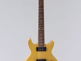 une guitare électrique jaune accrochée à un mur blanc