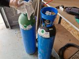 un homme qui se tient à côté de deux bouteilles de gaz