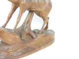a wooden sculpture of a deer and a bird on a log