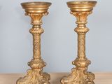 pair of antique brass candlesticks on wooden table against blue wall