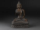 a bronze figure of a seated buddha on a pedestal