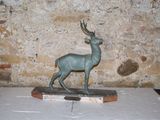 une statue représentant un cerf debout sur un socle en bois