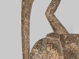 sculpture of an elephant made of wood with a long neck and tail