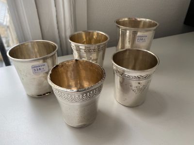 four silver cups are lined up on a white table