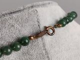 a close up of a green beaded bracelet on a mannequin dummy