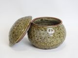 a small green pot with a lid on a white surface