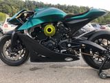 a green motorcycle parked in a parking lot next to some cars