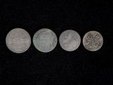 four different coins are shown in a row on a black surface