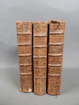three old books sitting on top of each other on a gray surface
