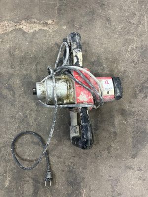 a drill that is laying on the ground next to a hose