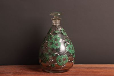a glass bottle with a green and black design on it