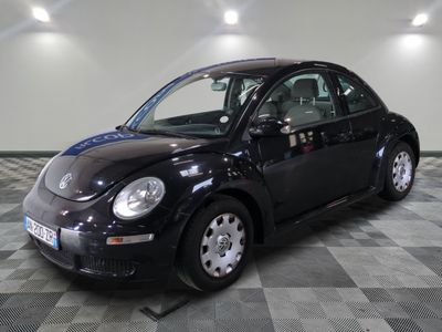 une photo d'une Coccinelle Volkswagen noire posée sur un sol à carreaux