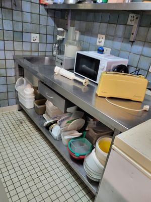 une cuisine équipée d'un évier, d'un micro-ondes, d'un lave-vaisselle et d'autres ustensiles posés sur le plan de travail