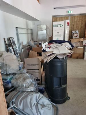 a trash can in the middle of a room filled with boxes and other items