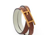 un gros plan sur un bracelet en cuir marron muni d'une boucle dorée