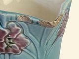 a blue vase with pink flowers on it on a white surface