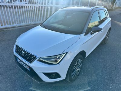 une voiture blanche garée sur un parking, à côté d'une clôture blanche