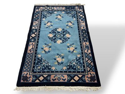 a blue rug with a floral design and fringes