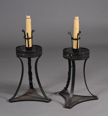 une paire de bougeoirs en fer forgé avec des bougies posées sur leurs socles