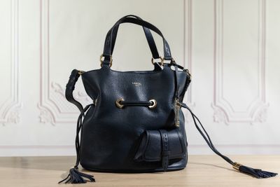 un sac à main en cuir noir orné de pompons, posé sur un parquet