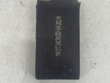 an old black book with writing on it sitting on a white surface