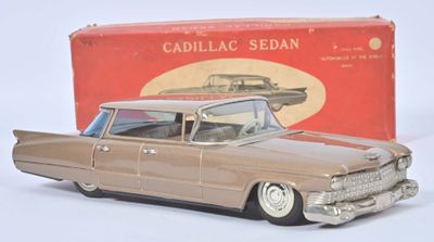 une petite voiture devant une boîte contenant des berlines Cadillac, posée sur une surface blanche