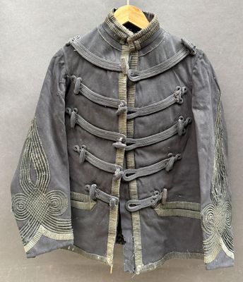 une veste militaire grise avec des passementeries dorées et des boutons, suspendue à un cintre