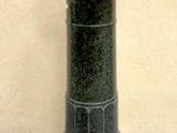 a black pedestal with a marble top on a cement floor