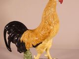 a figurine of a rooster on a green base