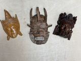 three wooden masks are sitting on a table next to each other