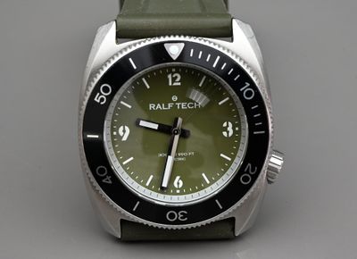 une montre avec un cadran vert sur un fond gris