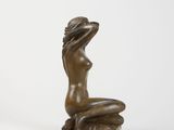 an image of a bronze statue of a woman sitting on a rock