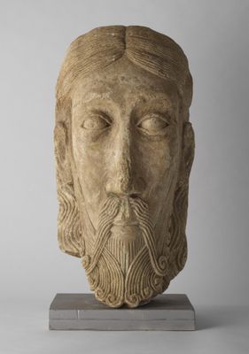 une tête en pierre représentant un homme barbu aux cheveux longs et à la barbe longue