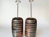 une paire de vases rayés de noir et de cuivre sur fond blanc