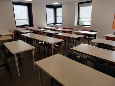 many tables and chairs in this empty classroom
