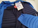 a blue and black jacket and a blue jacket on a bed