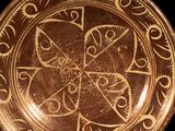 a brown plate with a design on it on a black background