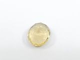 a close up of a yellow sapphire stone on a white surface
