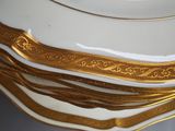 a stack of white plates with gold trims on them