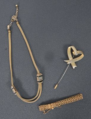 un collier, un bracelet et une broche posés sur un fond gris